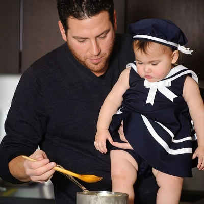 Scott holding his daughter while cooking.